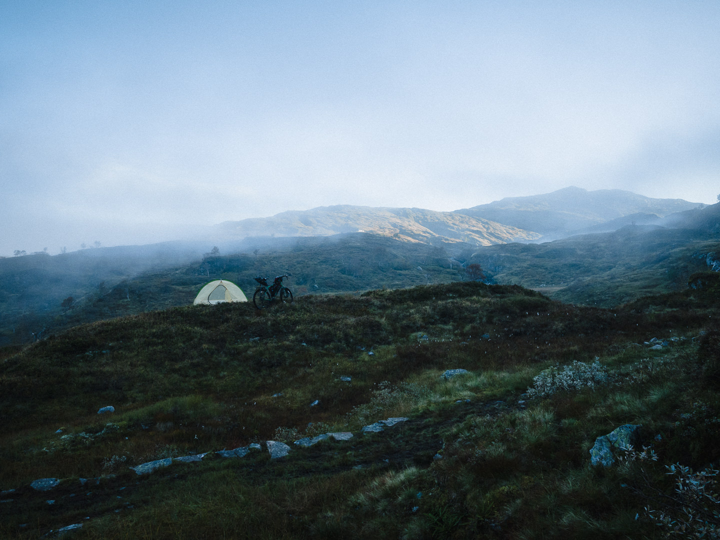 Morning landscape showing tent and distant fog in mountain landscape.