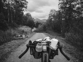 The familiar view over the handlebars. Gravel road view, seen from a bike saddle. Mountains in the distance.